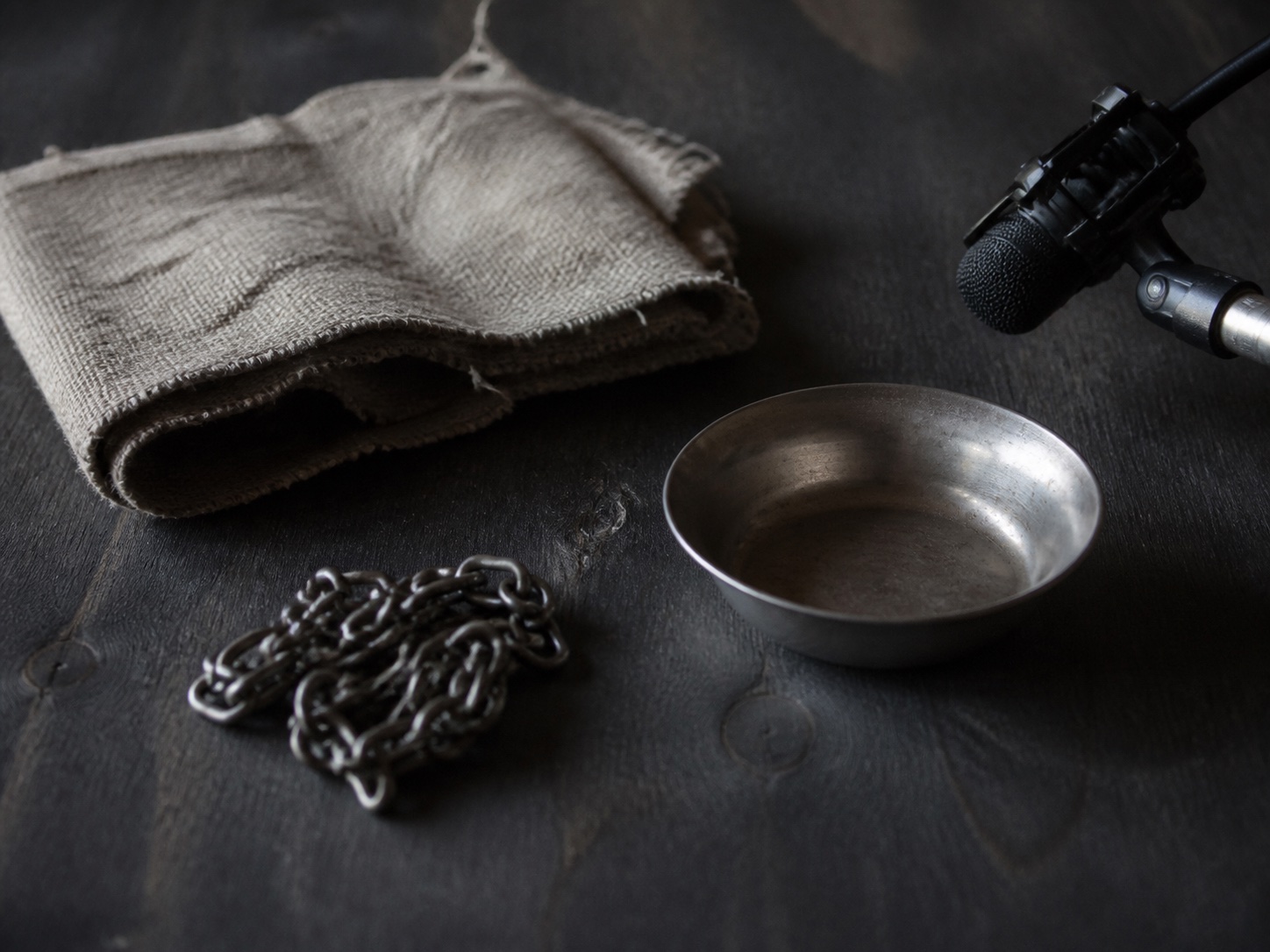 AI-generated tactile study of fabric, a coiled chain and metal bowl beside a microphone.