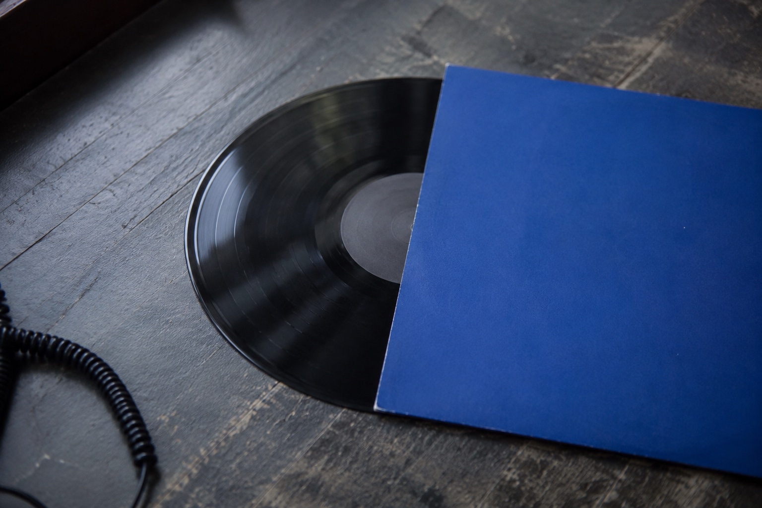 AI-generated still life of a vinyl record in a blue sleeve on a worn listening table.